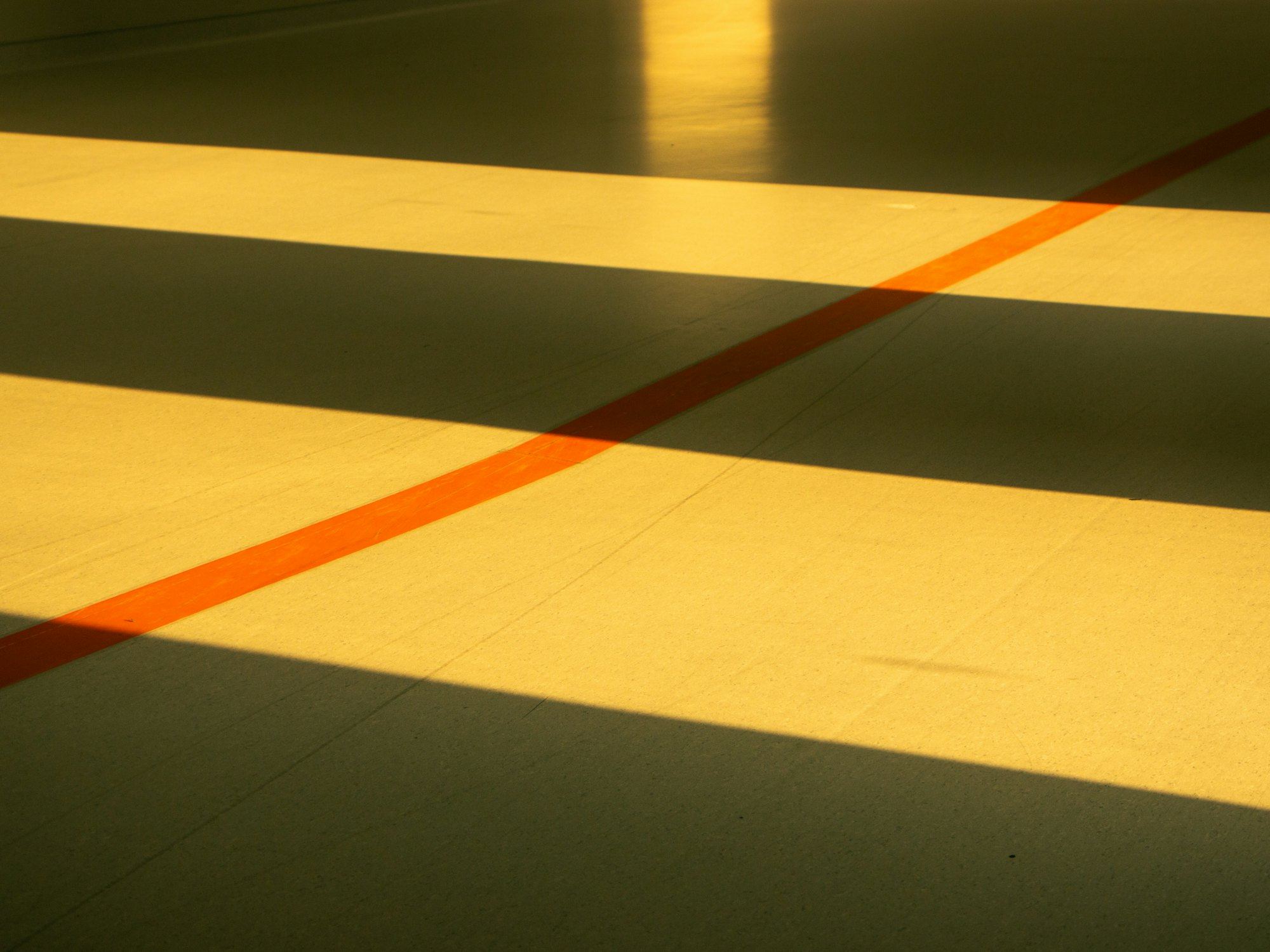 Shadows on a yellow gym floor with an orange line