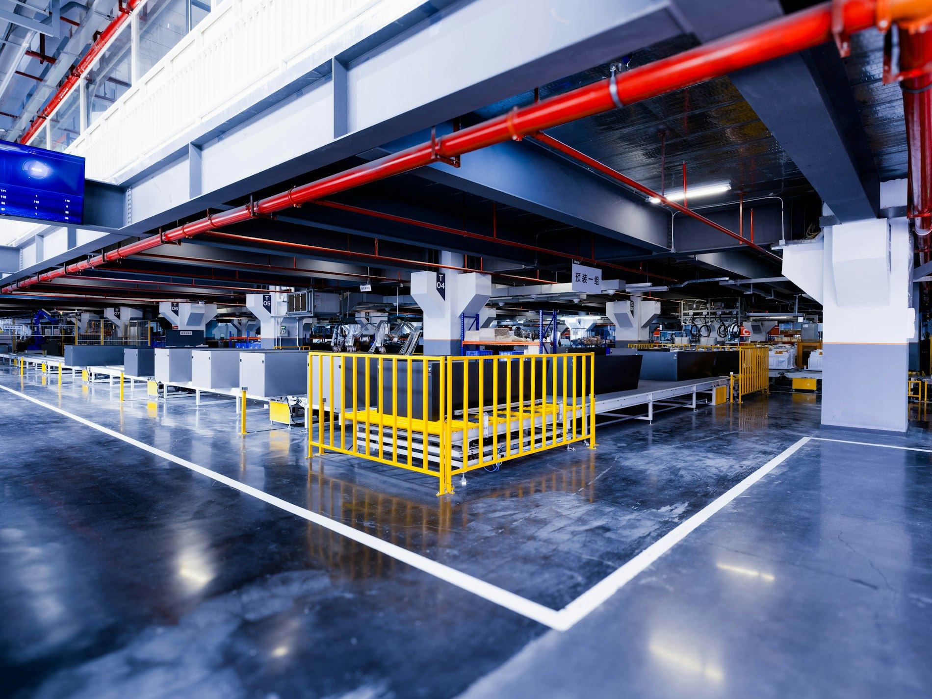 Industrial building interior with red pipework and yellow barriers