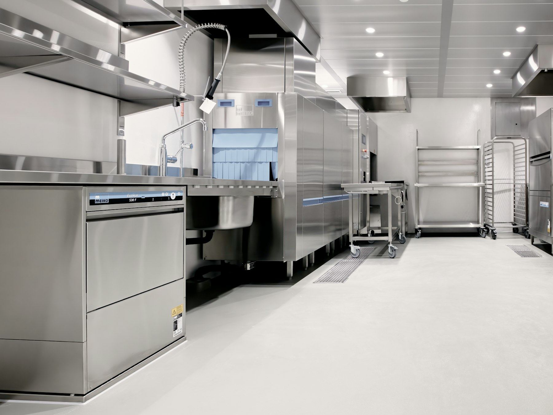 A commercial kitchen with stainless steel equipment and a light floor