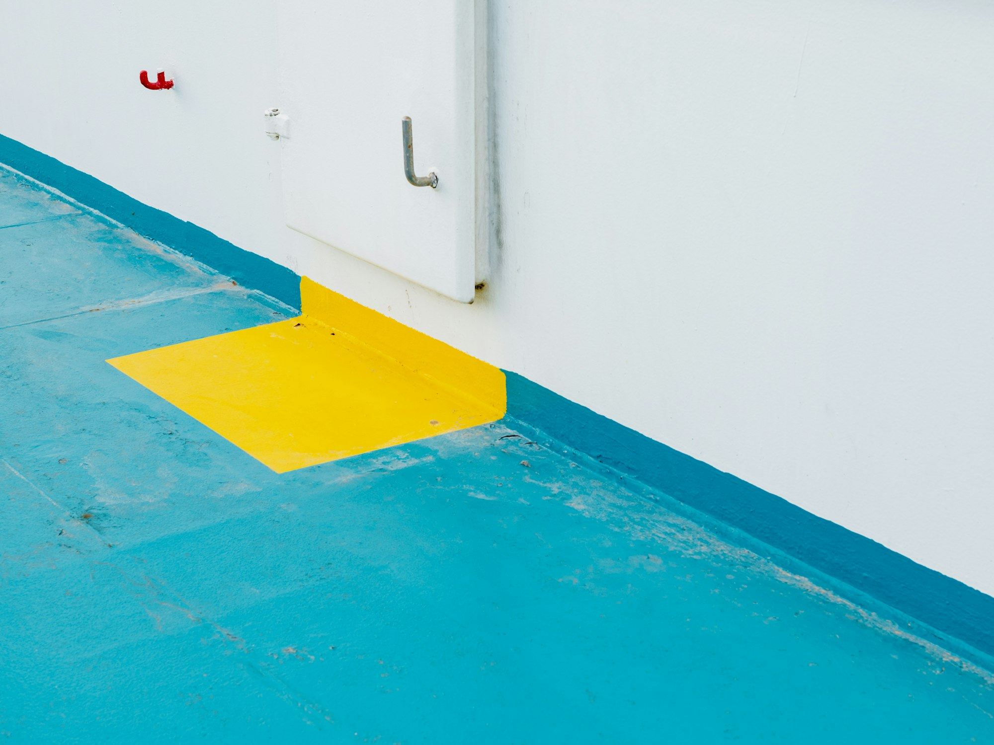 Close-up of a blue resin floor meeting a yellow ramp and white wall